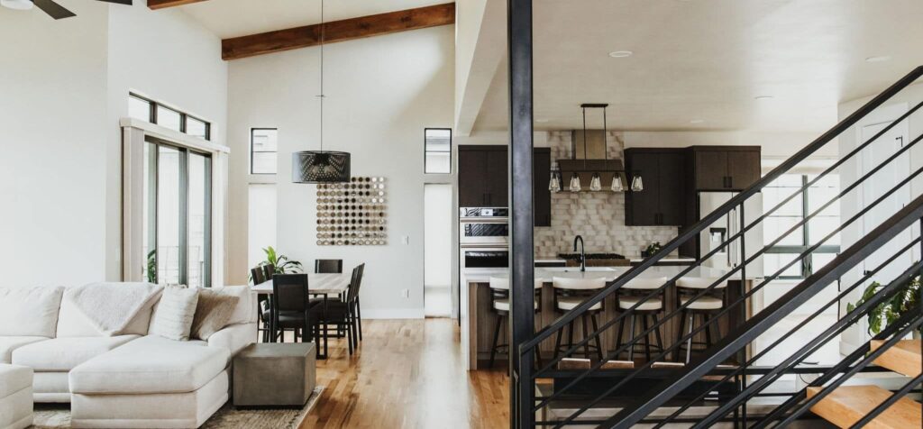 A wide shot inside an open floorplan, showcasing a living room, kitchen, and dining room.